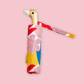Compact folding umbrella with duck-shaped wooden handle and colorful floral sleeve on pink background.