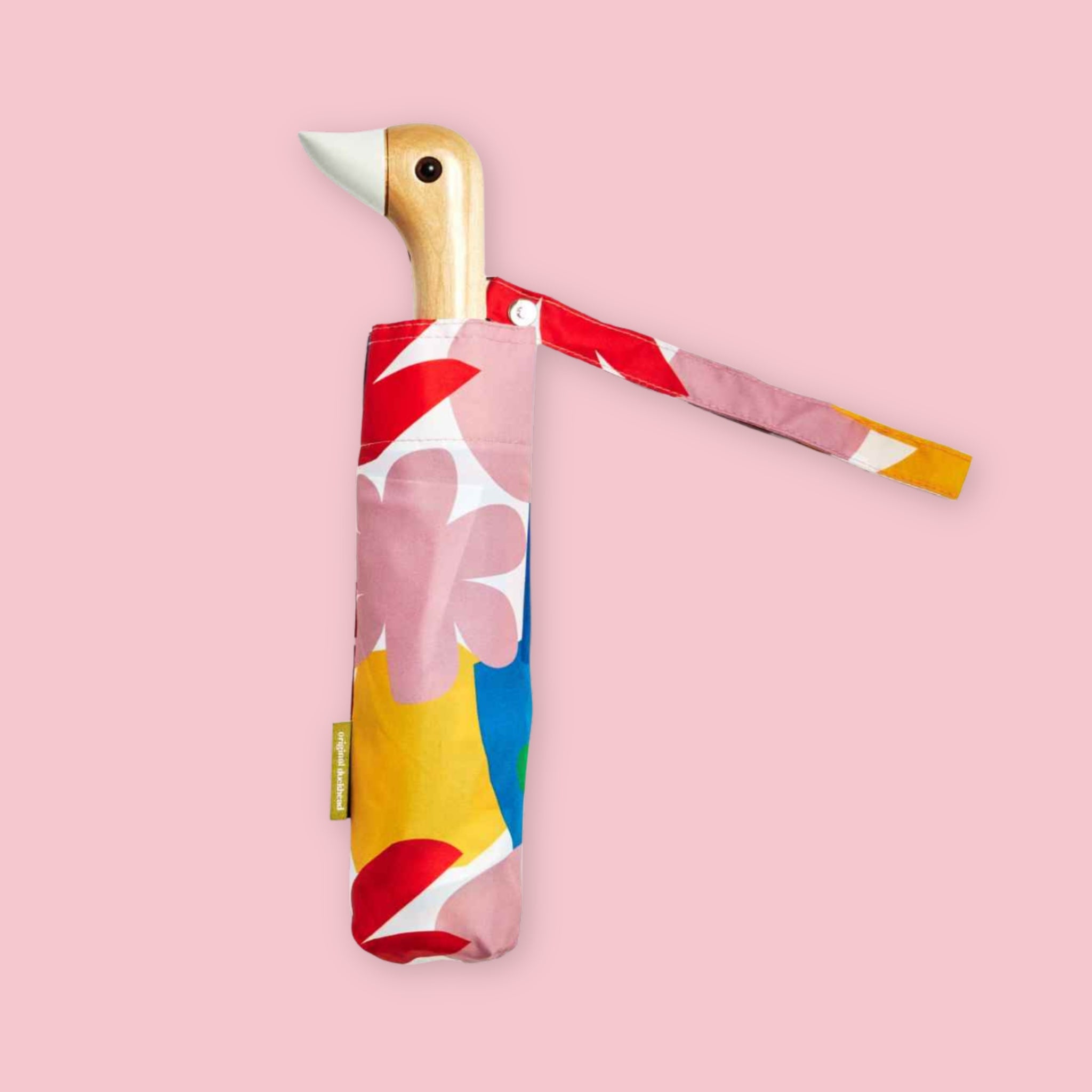 Compact folding umbrella with duck-shaped wooden handle and colorful floral sleeve on pink background.