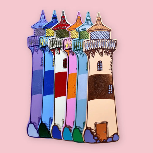Set of colorful Ark Colour Design leather bookmarks shaped like lighthouses, shown standing together on a pink background.