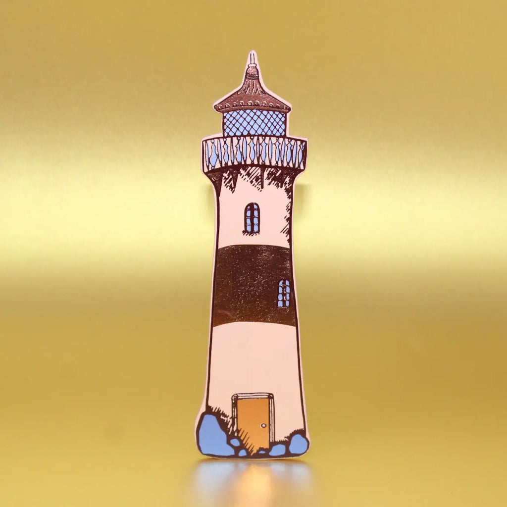 Peach lighthouse-shaped leather bookmark from an Ark Colour Design book, shown standing on a gold background.