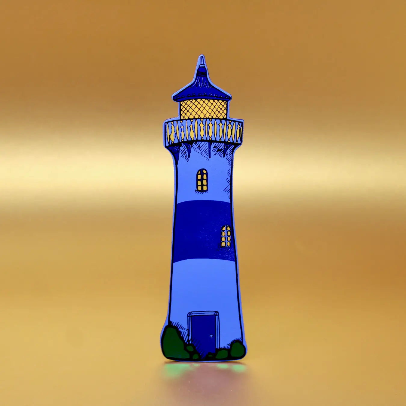 Blue lighthouse-shaped leather bookmark from an Ark Colour Design book, shown standing on a gold background.
