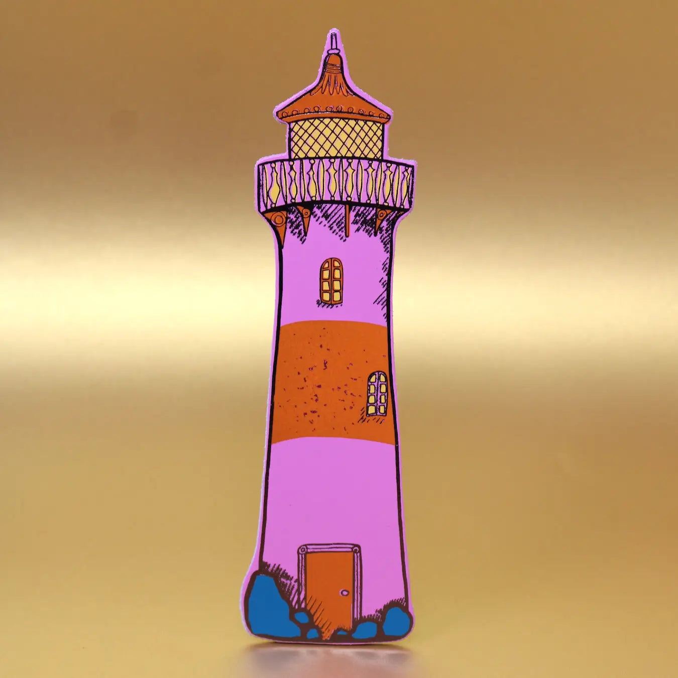 Hot pink lighthouse-shaped leather bookmark from an Ark Colour Design book, shown standing on a gold background.