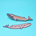 Two pink whale-shaped bookmarks, one with star designs along its body and one lettered "Come sail with me," on a light blue background.