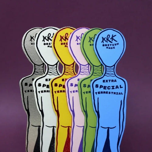 Six alien-shaped bookmarks in gold, white, yellow, pink, green, and blue, each lettered "Ark British Made, Extra Special Terrestrial," on a purple background.