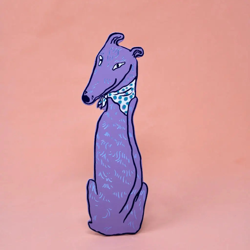 Lilac greyhound-shaped bookmark wearing a blue polka dot bandana, sitting upright, on a peach background.