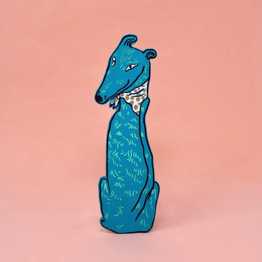 Blue greyhound-shaped bookmark wearing a orange polka dot bandana, sitting upright, on a peach background.