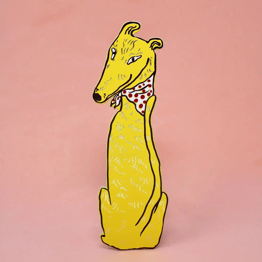 Yellow greyhound-shaped bookmark wearing a red polka dot bandana, sitting upright, on a peach background.