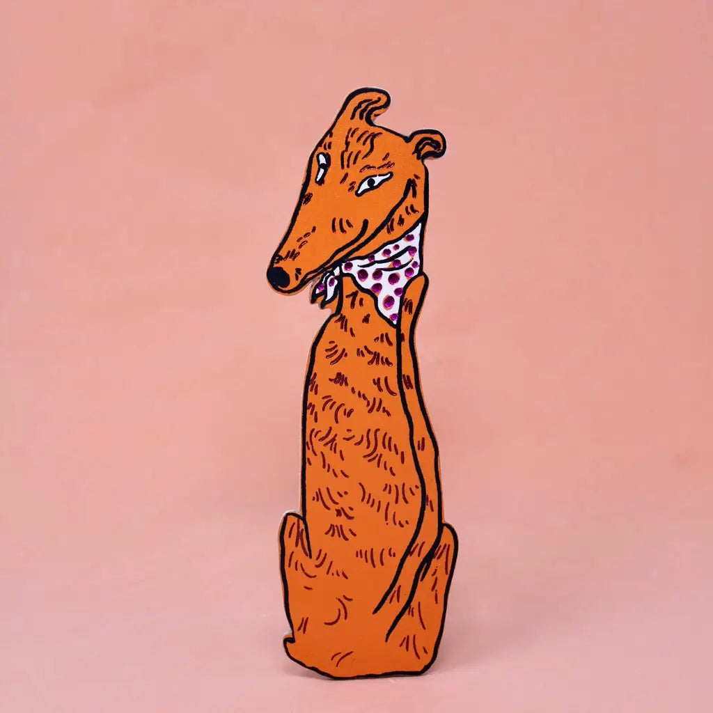 Orange greyhound-shaped bookmark wearing a pink polka dot bandana, sitting upright, on a peach background.