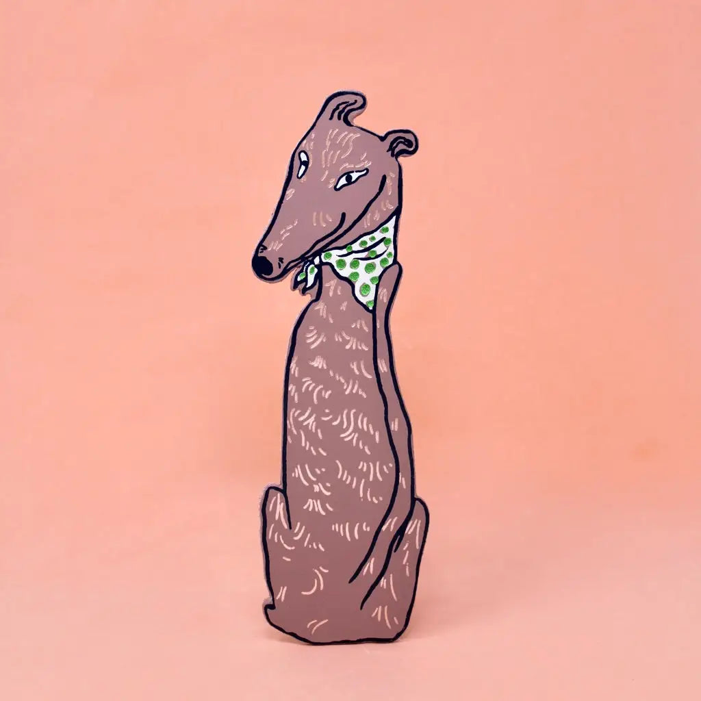 Greyhound-shaped bookmark wearing a green polka dot bandana, sitting upright, on a peach background.