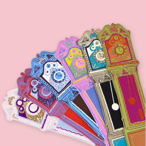 Set of colorful Ark Colour Design leather bookmarks shaped like grandfather clocks, fanned out on a pink background.