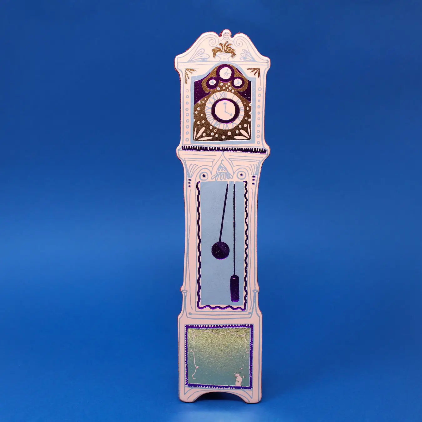 Cream Ark Colour Design leather bookmark shaped like a colorful grandfather clock, shown standing on a blue background.