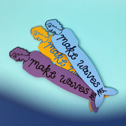 Set of three Ark Colour Design leather bookmarks shaped like mermaids face down with text 'Make Waves', shown layered on a turquoise background.