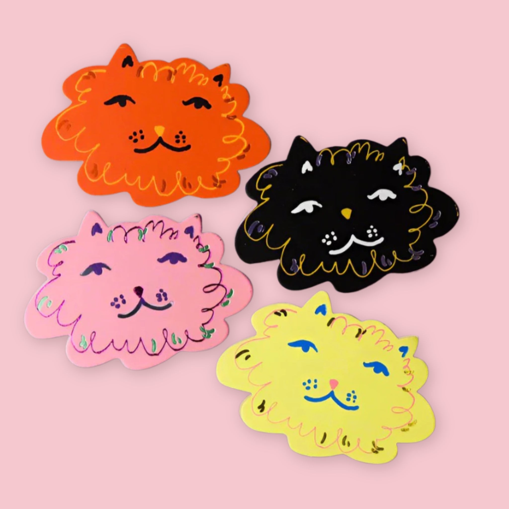 Four cat-shaped leather coasters by Ark Colour Design in orange, black, pink, and yellow on a pastel pink background, each with a whimsical smiling cat face illustration.
