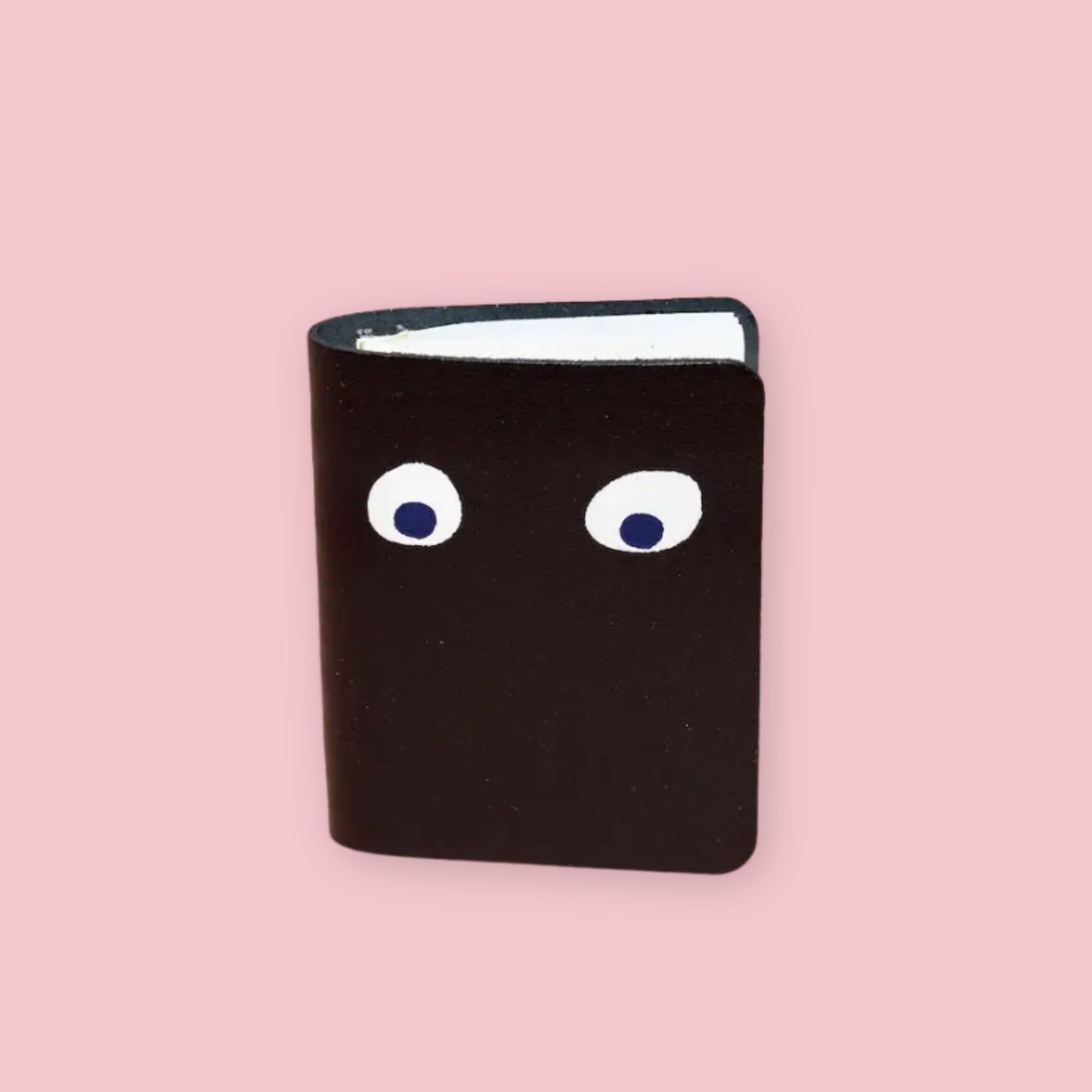 Ark Colour Design leather googly eye notebook in black with foil-embossed eyes on a pink background