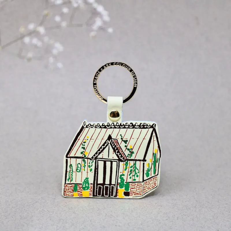 Ark Colour Design greenhouse keychain with yellow strap, gold ring, and illustrated cream greenhouse design.