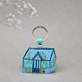 Ark Colour Design greenhouse keychain with yellow strap, gold ring, and illustrated blue greenhouse design.