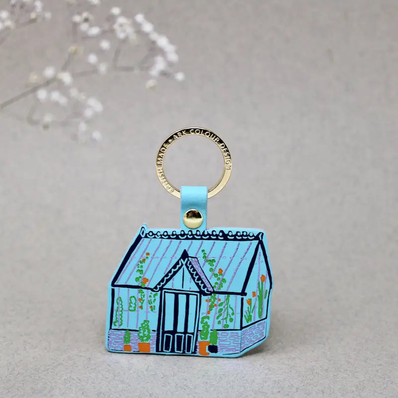 Ark Colour Design greenhouse keychain with yellow strap, gold ring, and illustrated blue greenhouse design.