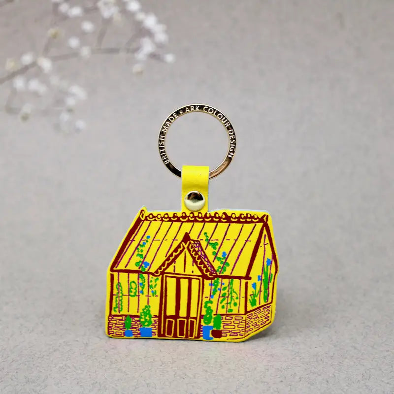 Ark Colour Design greenhouse keychain with yellow strap, gold ring, and illustrated yellow greenhouse design.