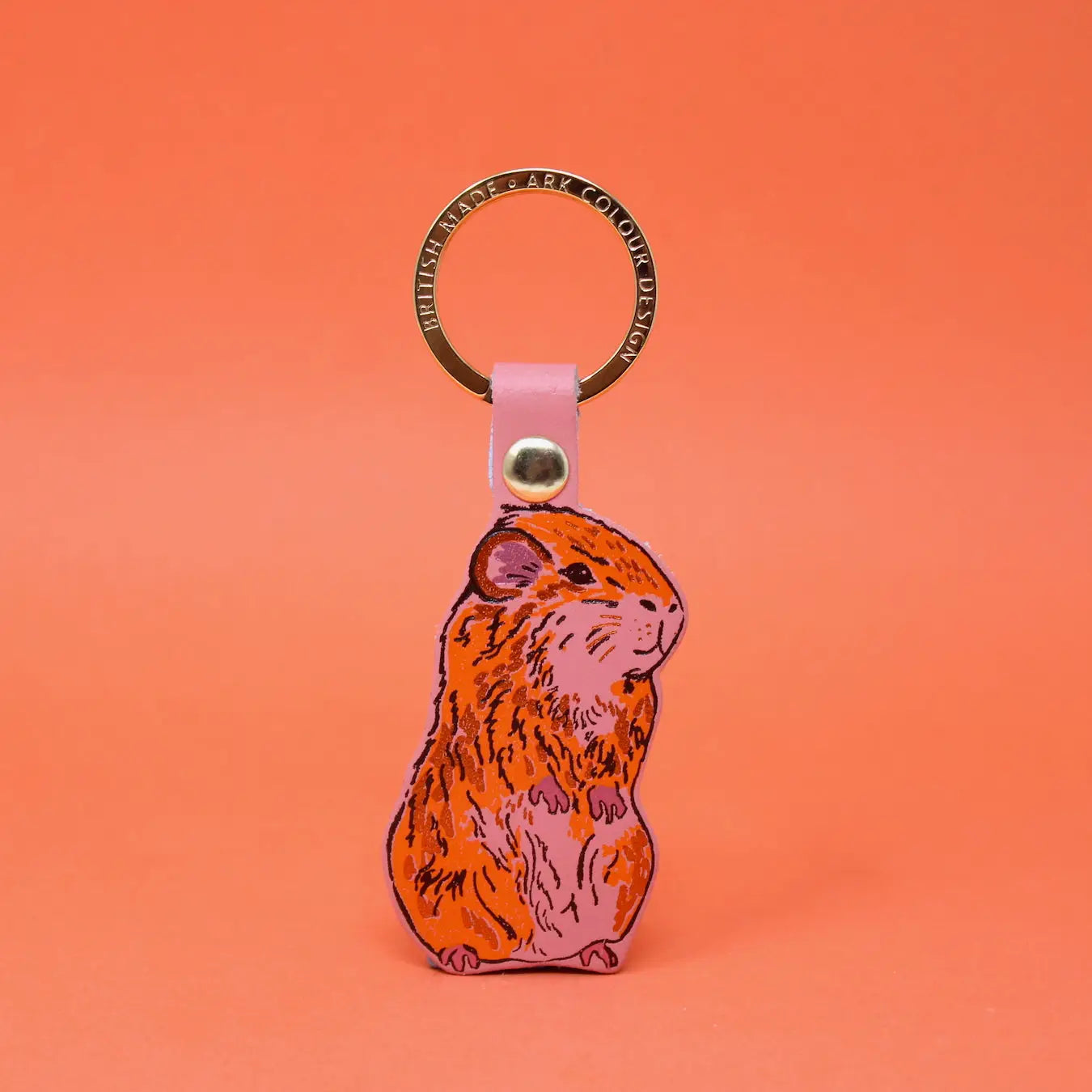 Ark Colour Design guinea pig keychain with a gold ring and illustrated orange, pink, and tan guinea pig design.