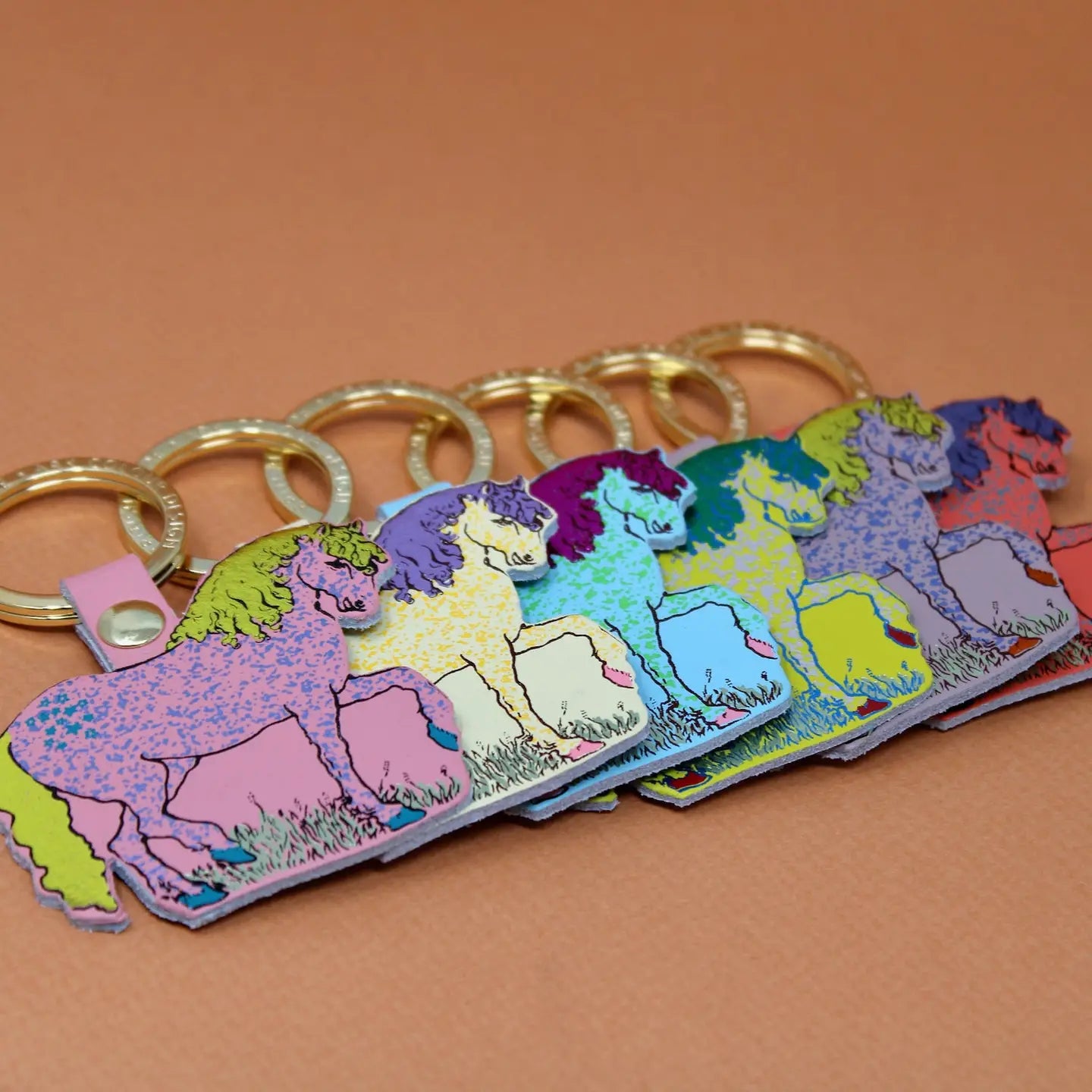 Ark Colour Design horse keychains in assorted bright colors, arranged in a row with gold key rings.