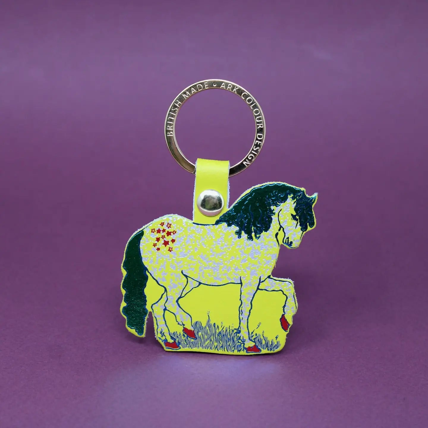 Ark Colour Design horse keychain with gold ring, acid green leather loop, and illustrated green horse design on a purple background.