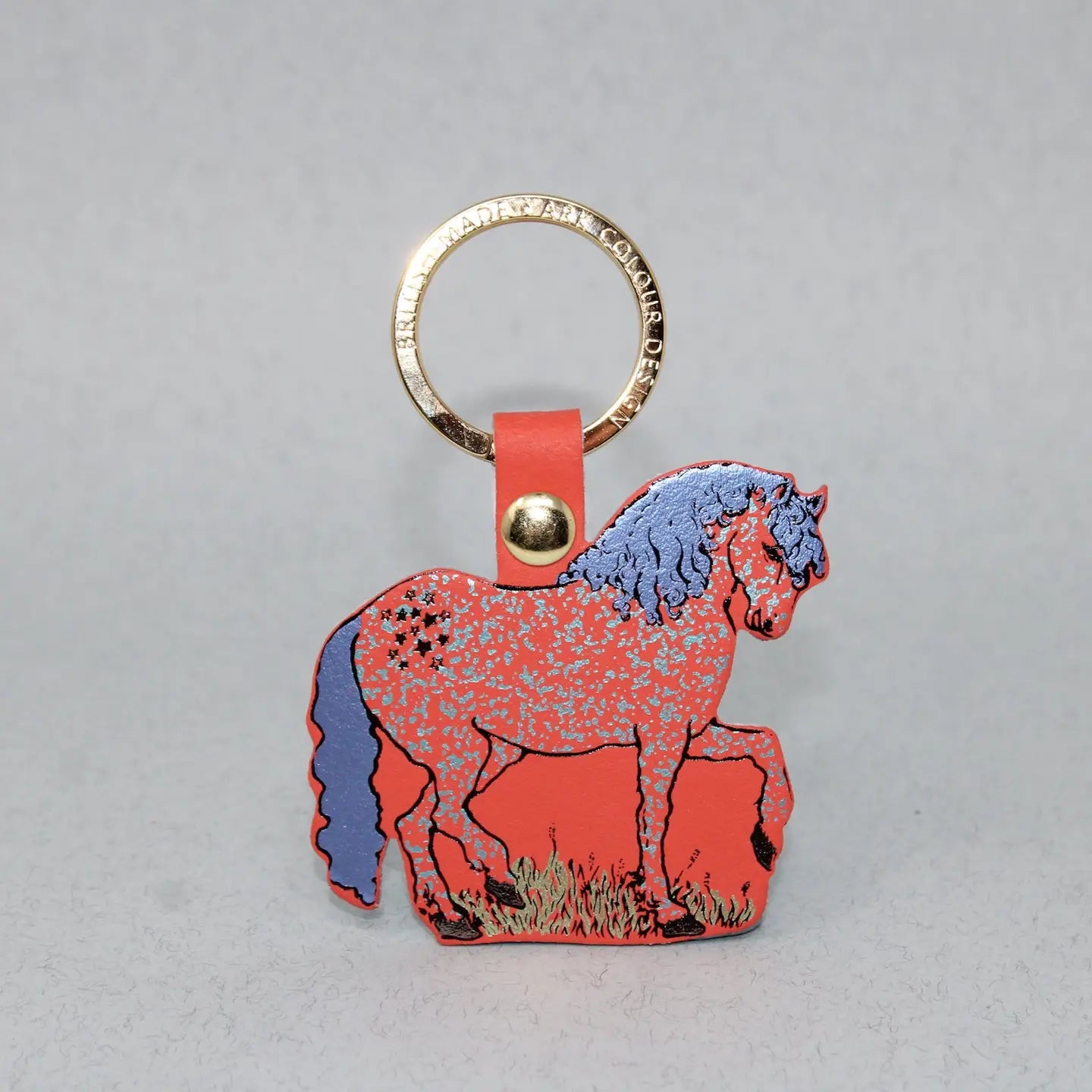 Ark Colour Design horse keychain with gold ring, coral leather loop, and illustrated coral horse design on a gray background.