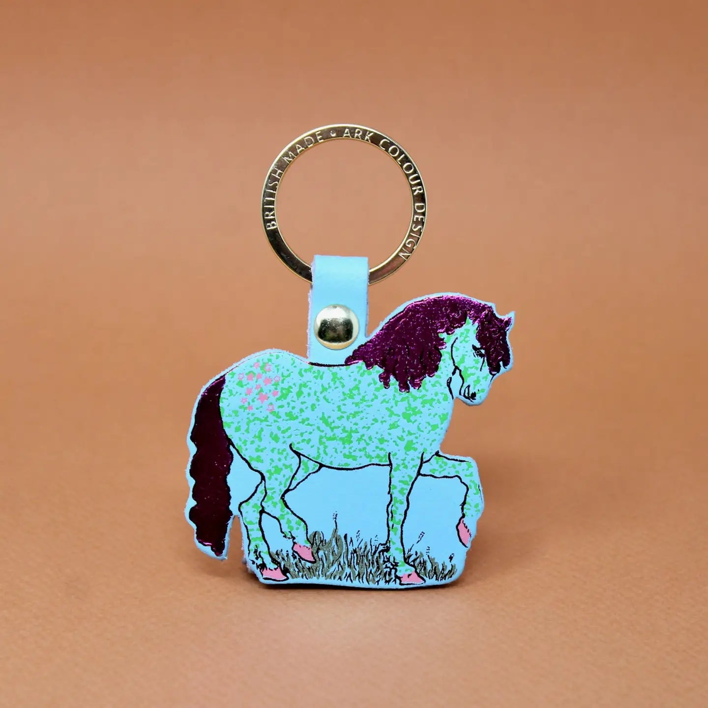 Ark Colour Design horse keychain with gold ring, blue leather loop, and illustrated blue horse design on an orange background.
