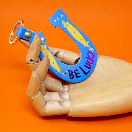 Ark Colour Design blue horseshoe keychain with “Be Lucky” text, and gold key ring.