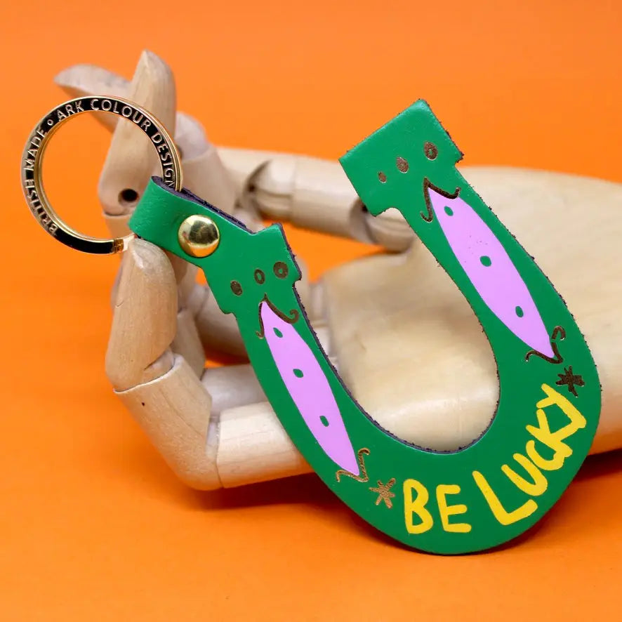 Ark Colour Design green horseshoe keychain with  “Be Lucky” text, and gold key ring.