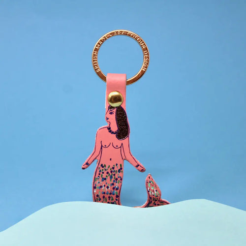 Pink mermaid keychain with gold accents on a blue background