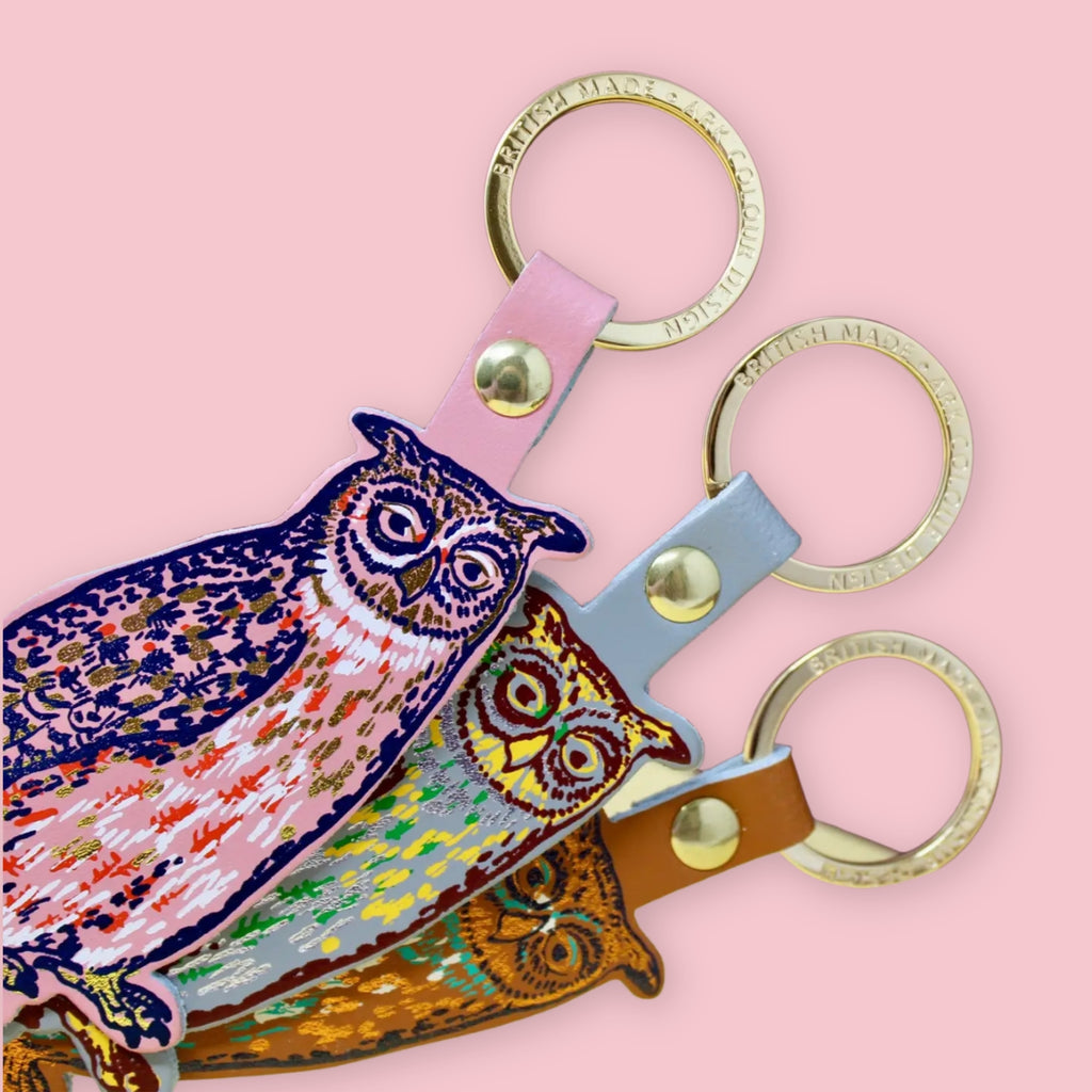 Ark Colour Design owl keychains in three color styles, shown with gold key rings on pink background.