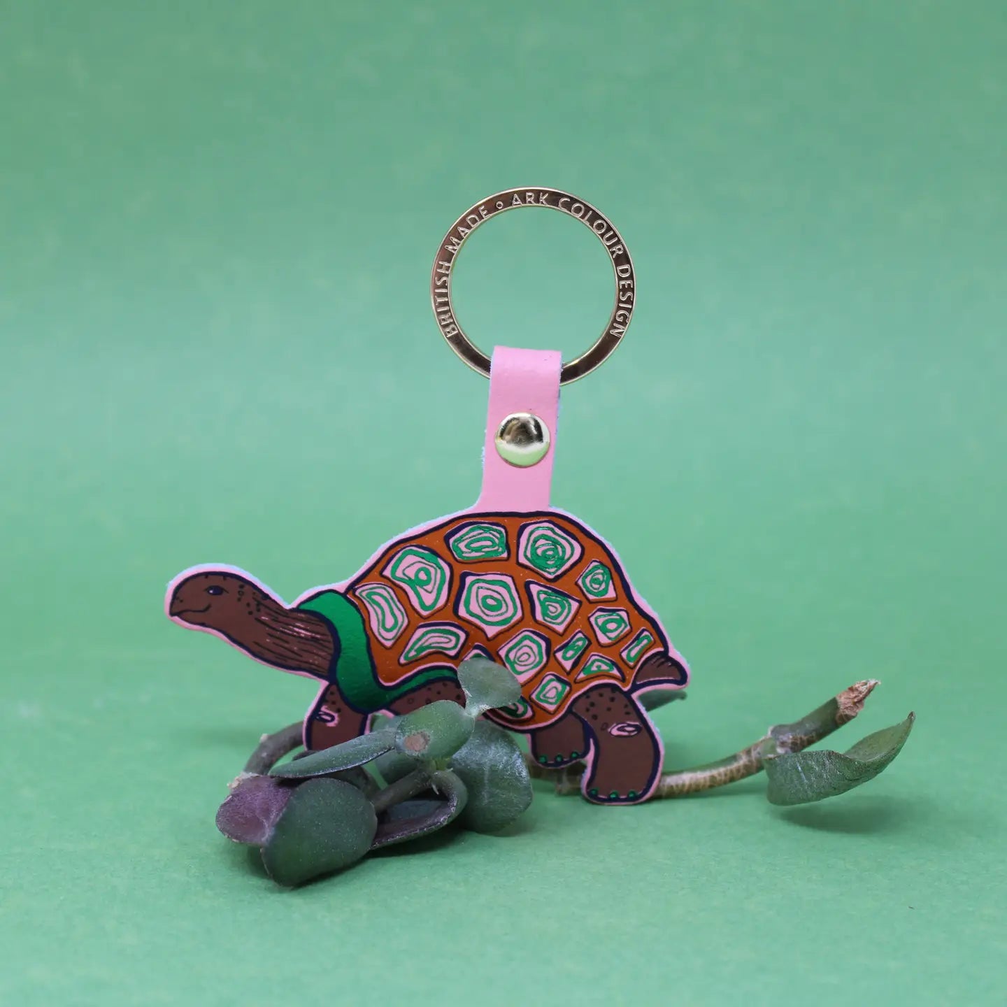 Ark Colour Design tortoise keychain with pink strap, gold ring, and colorful illustrated turtle design.