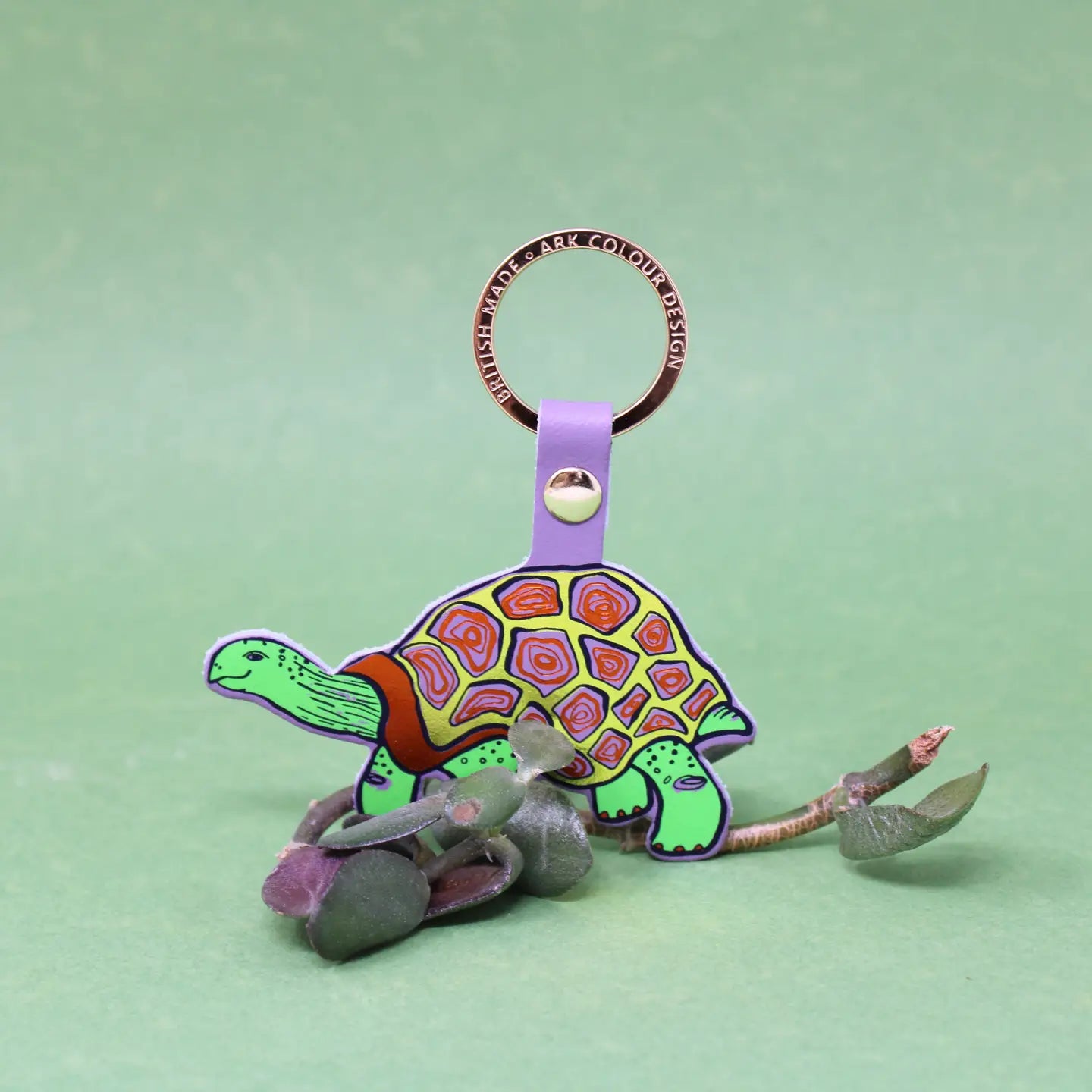 Ark Colour Design tortoise keychain with lilac strap, gold ring, and colorful illustrated turtle design.
