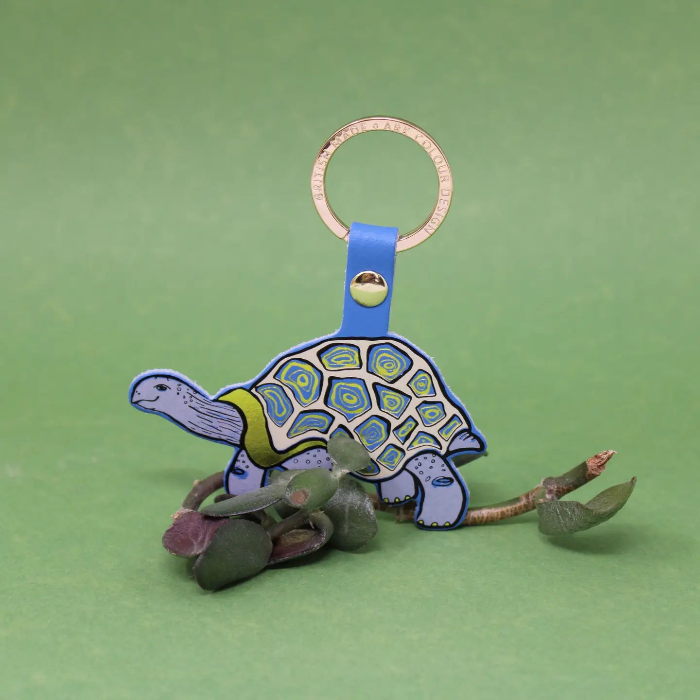 Ark Colour Design tortoise keychain with blue strap, gold ring, and colorful illustrated turtle design.