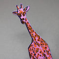 Close-up of a pink and orange giraffe-shaped leather bookmark on a gray background.