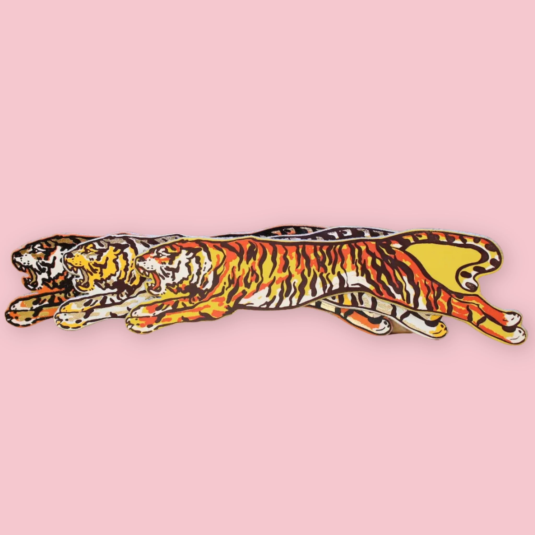 Set of three Ark Colour Design leather bookmarks shaped like leaping tigers, shown layered on a pink background.