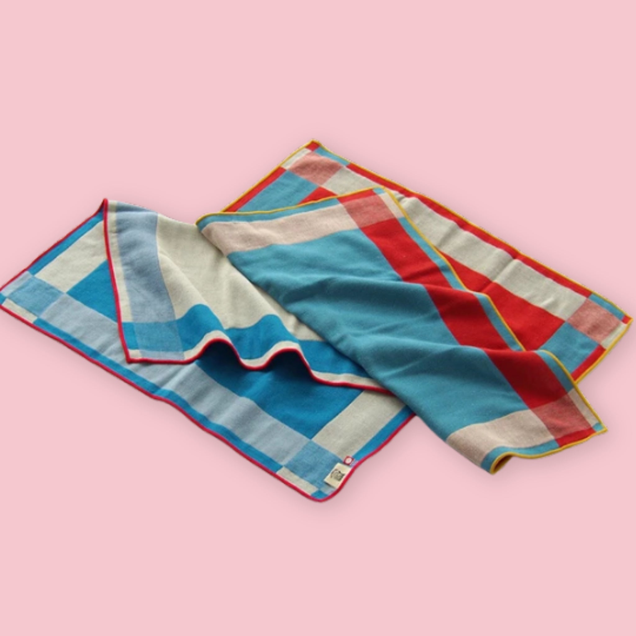 Imabari BLT Towels in Bold Blue Stripe and Bold Red Stripe styles loosely folded on a pink background