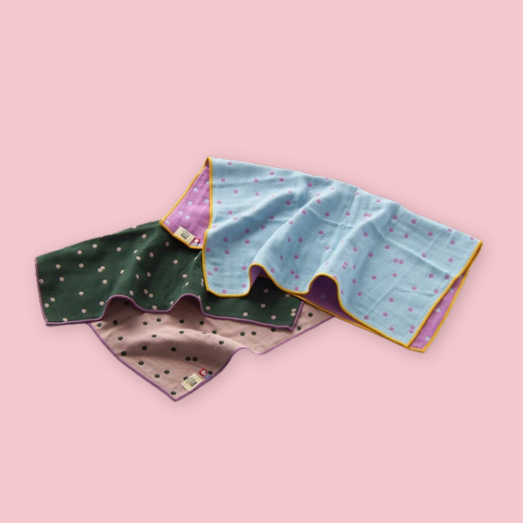 Imabari BLT Towels in Green Dot and Blue Dot styles loosely folded on a pink background