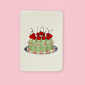Canonbury Press greeting card featuring an illustrated green chartreuse cake topped with bright red cherries and small floral decorations, centered on a soft cream background.