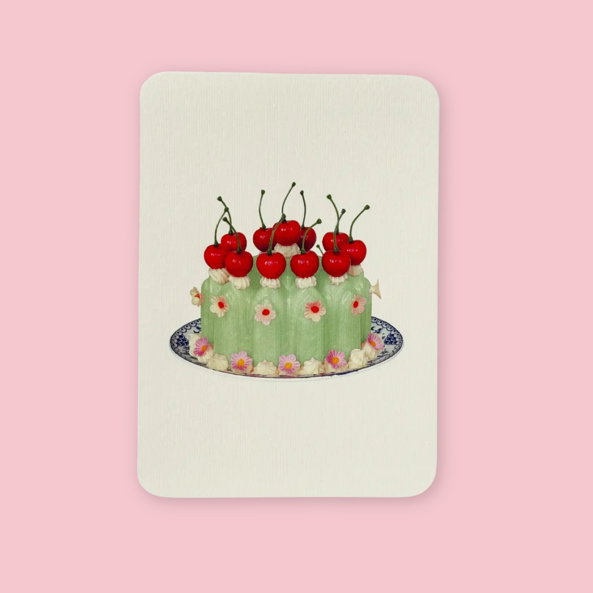 Canonbury Press greeting card featuring an illustrated green chartreuse cake topped with bright red cherries and small floral decorations, centered on a soft cream background.