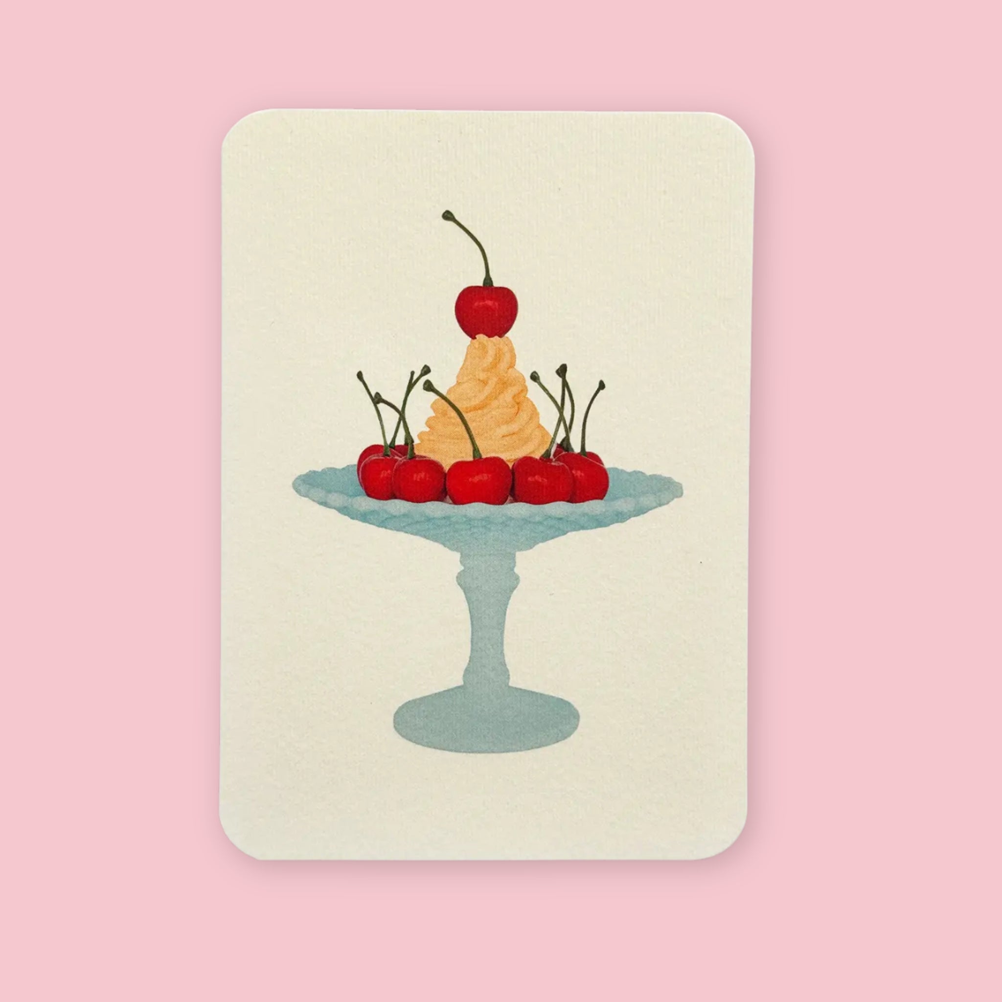 Canonbury Press Greeting card featuring an illustrated mandarin cream dessert on a blue pedestal plate, topped and surrounded with red cherries.