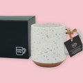 Chips Mug in Orange Splash with multicolor speckled glaze and branded black gift box on a pink background