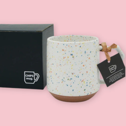 Chips Mug in Orange Splash with multicolor speckled glaze and branded black gift box on a pink background