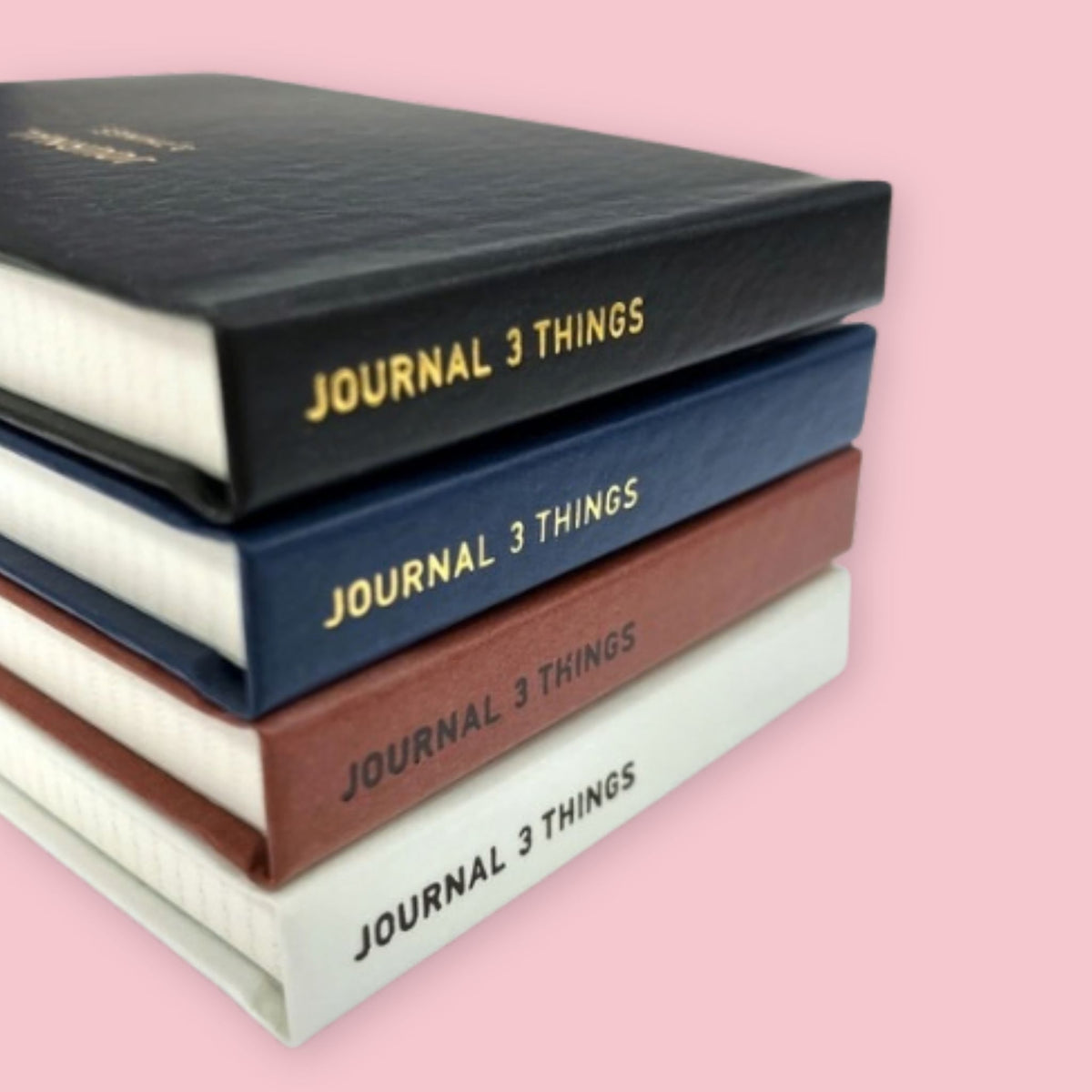 Stack of Daigo Mini Easy Journal 3 Things notebooks in black, navy, dark red, and white on a pink background.