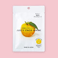 Japanese yuzu juicy face mask packet with a yellow citrus fruit illustration, shown on a pink background.