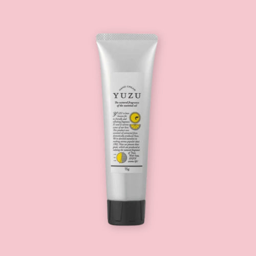 Silver tube of yuzu hand cream with a black cap, shown upright on a pink background.