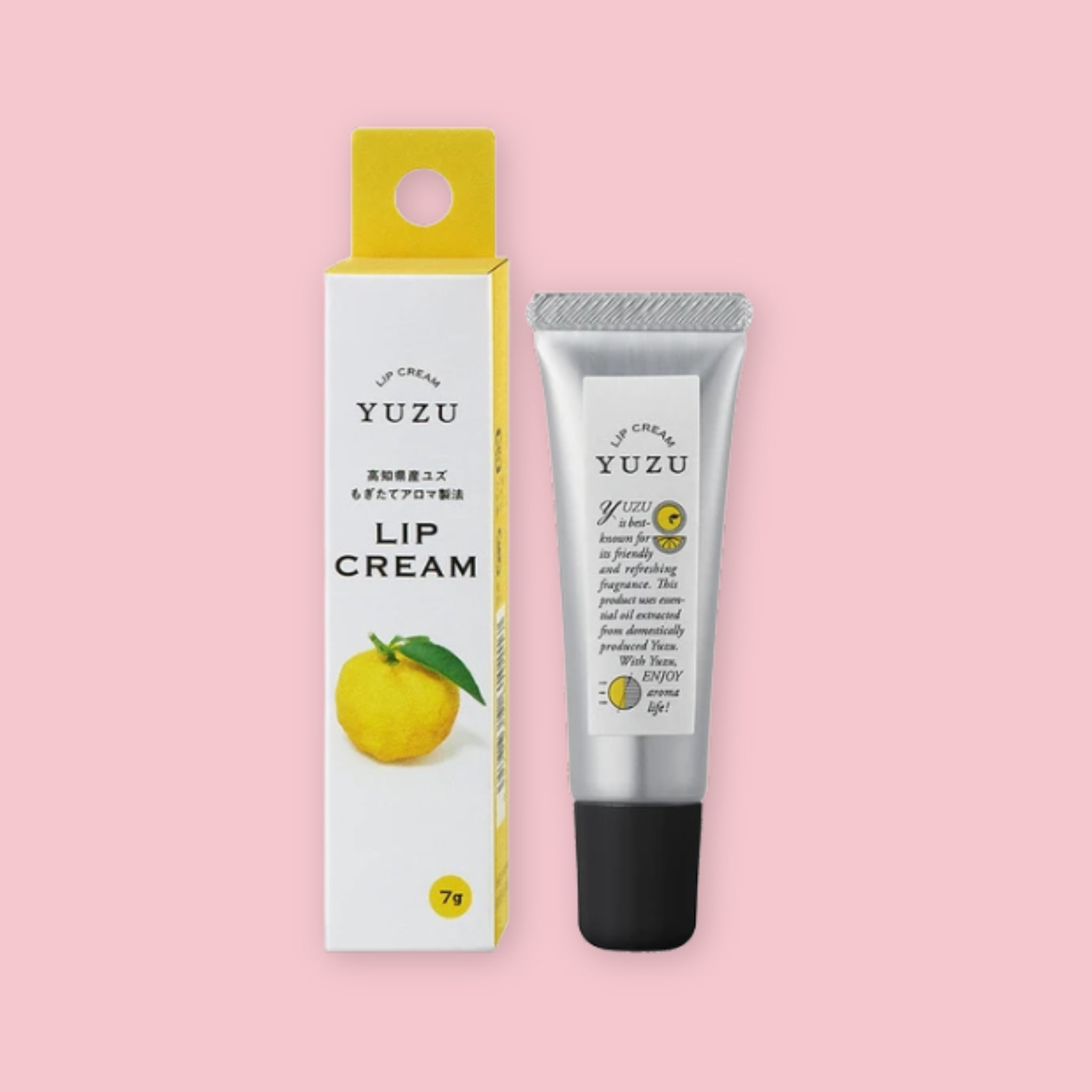 Yuzu lip cream in a silver tube with a black cap, shown beside its white and yellow box on a pink background.