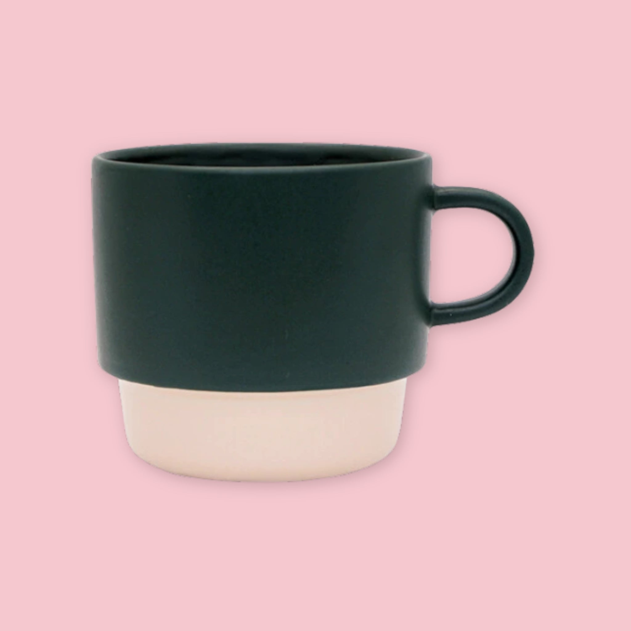 El Commun mug in dark green with a cream base on a pink background.