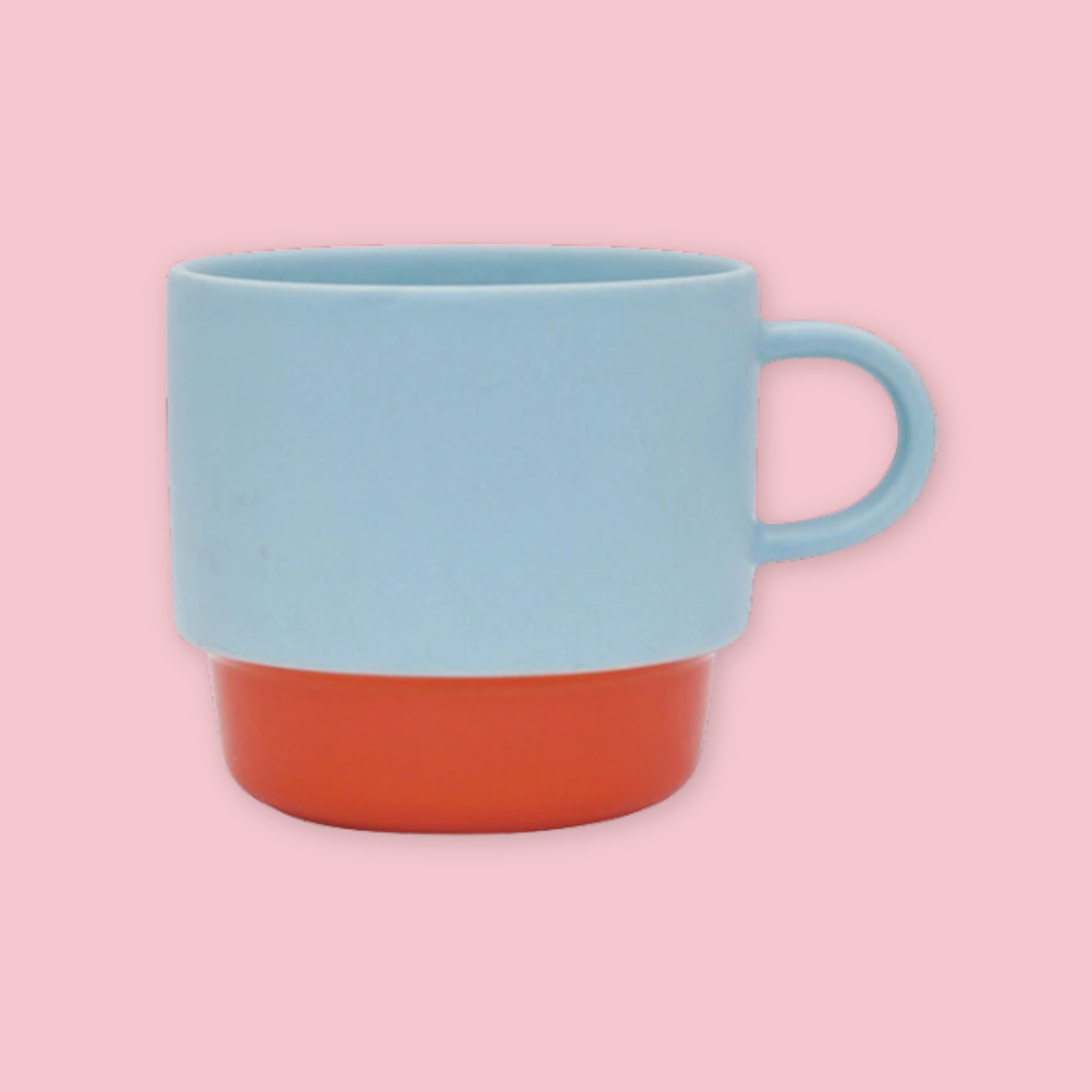El Commun mug in light blue with orange base on a pink background