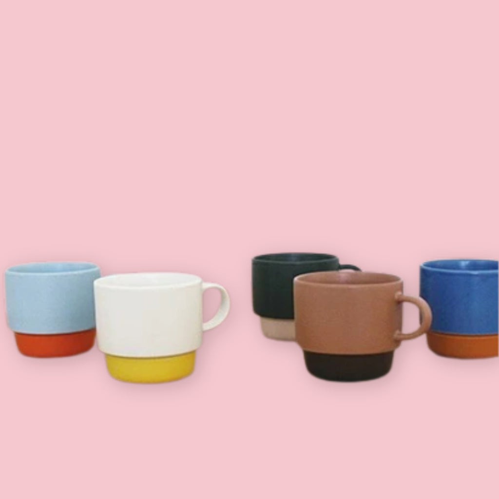 El Commun mugs in all five colorways arranged together on a pink background.